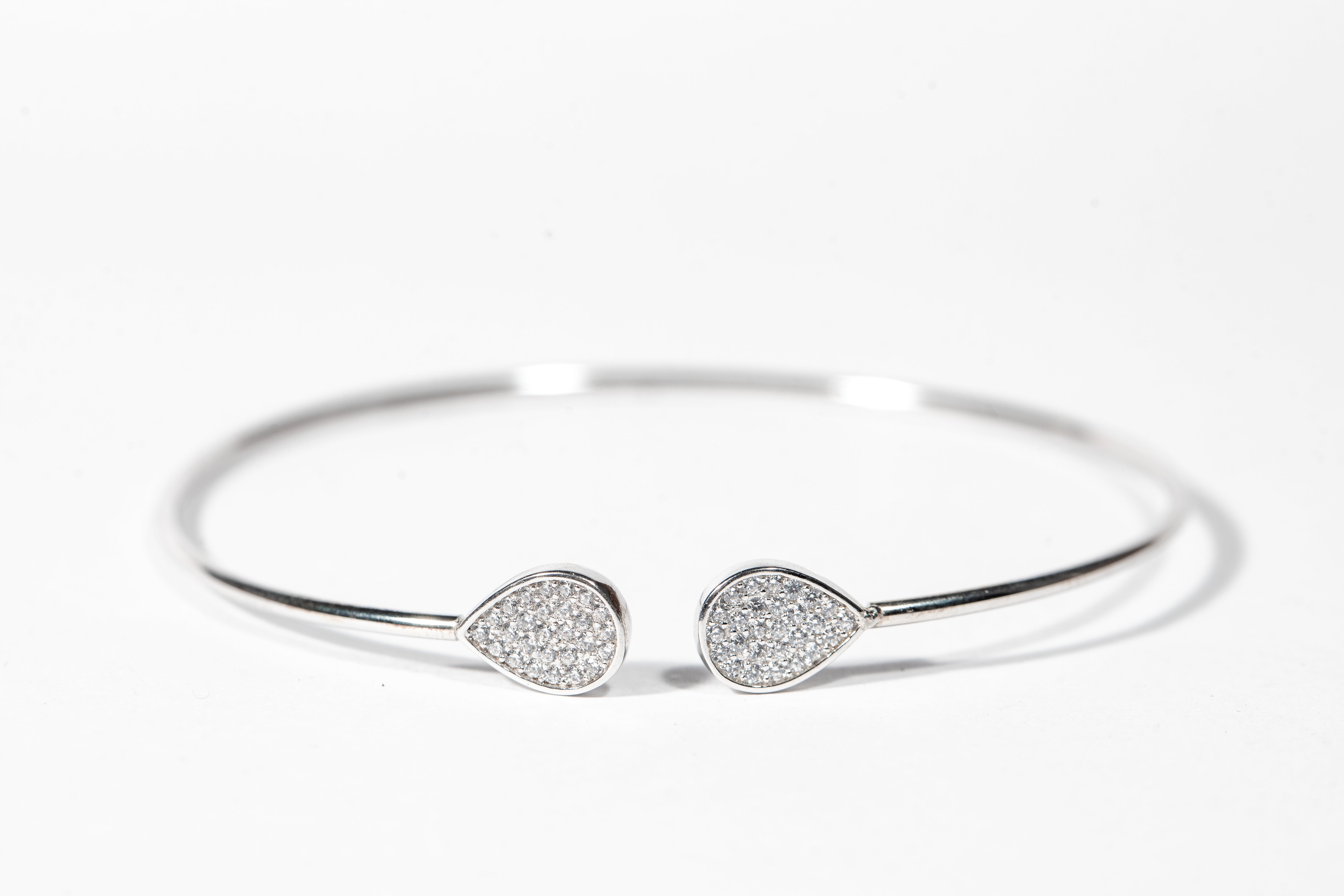 Sterling silver open cuff bangle featuring pear shaped accents embellished with cubic zirconia