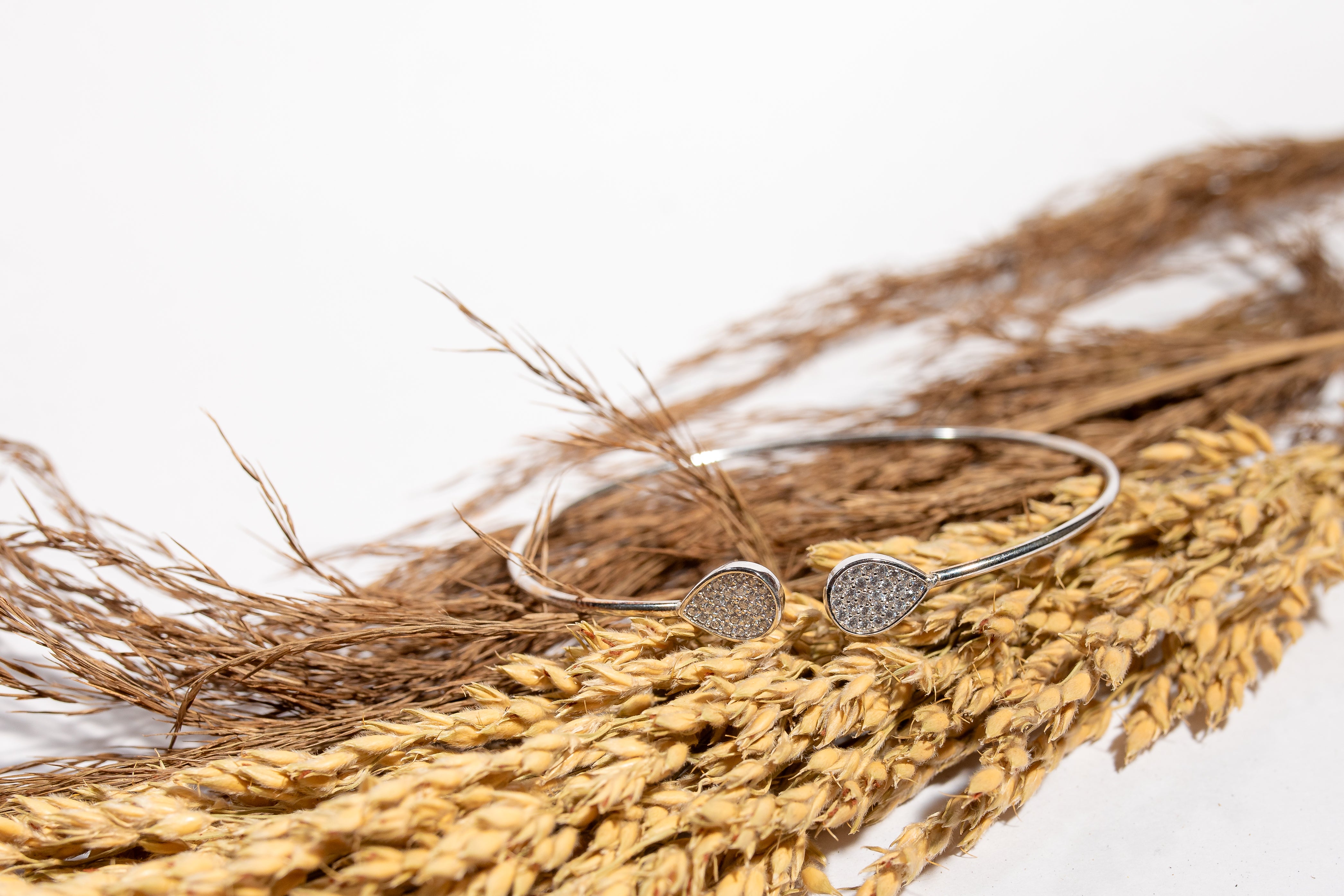 Sterling silver open cuff bangle featuring pear shaped accents embellished with cubic zirconia